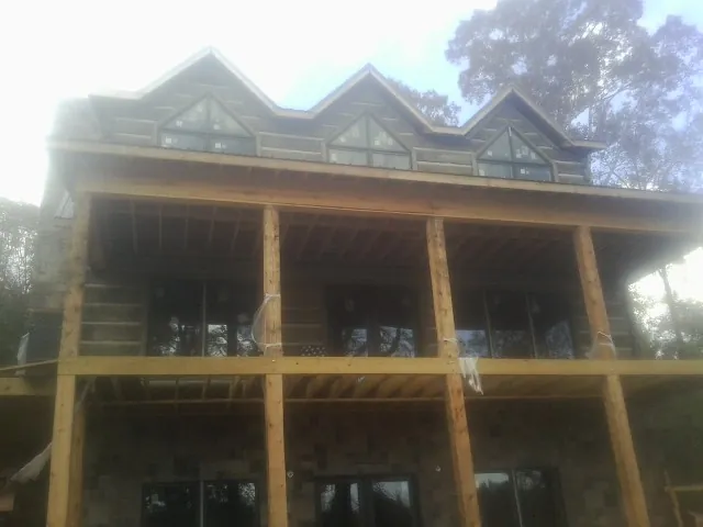 Dormers and porch framing on a large log home under construction — Roof Coating work by our crew in Crandon