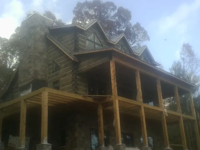 Stone chimney and dormers on a large log home with a timber porch in Crandon