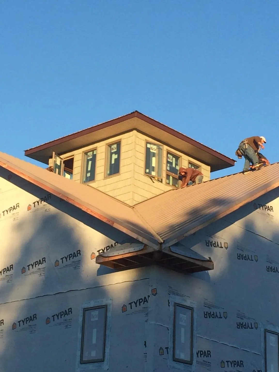 Roofers working around a rooftop cupola on a new metal roof at sunset — Roof Waterproofing in Crandon by Roofing Brothers